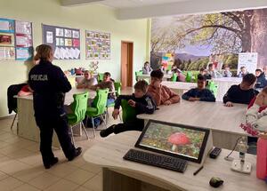 Policjantka i uczniowie podczas zajęć w klasie szkolnej.