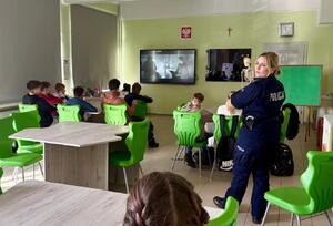 Policjantka i uczniowie podczas zajęć w klasie szkolnej.