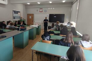 Policjantka i uczniowie podczas zajęć w klasie szkolnej.