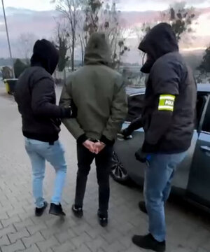 Policjanci prowadzą zatrzymanego.