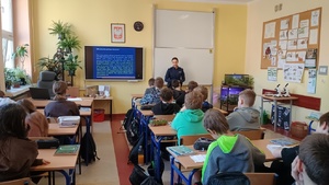 Policjantka i uczniowie podczas pogadanki w sali lekcyjnej w szkole.