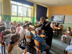 Policjantka i uczniowie podczas zajęć w klasie szkolnej.