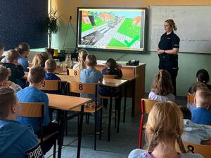 Policjantka i uczniowie podczas zajęć w klasie szkolnej.