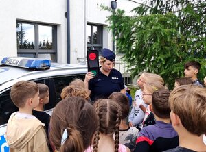 Policjantka podczas rozmów z uczniami na terenie przyszkolnym.