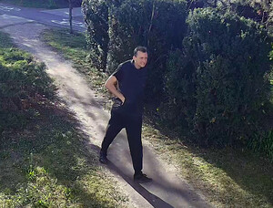 wizerunek podejrzewanego mężczyzny idącego po terenie zielonym
