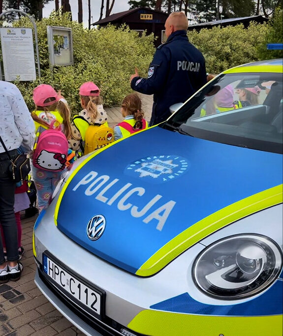 radiowóz, policjant i dzieci uczestniczące w wydarzeniu