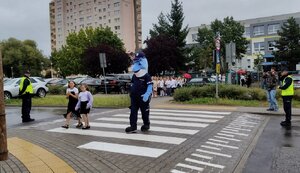 Policjanci i uczniowie podczas zajęć w rejonie przejścia dla pieszych.